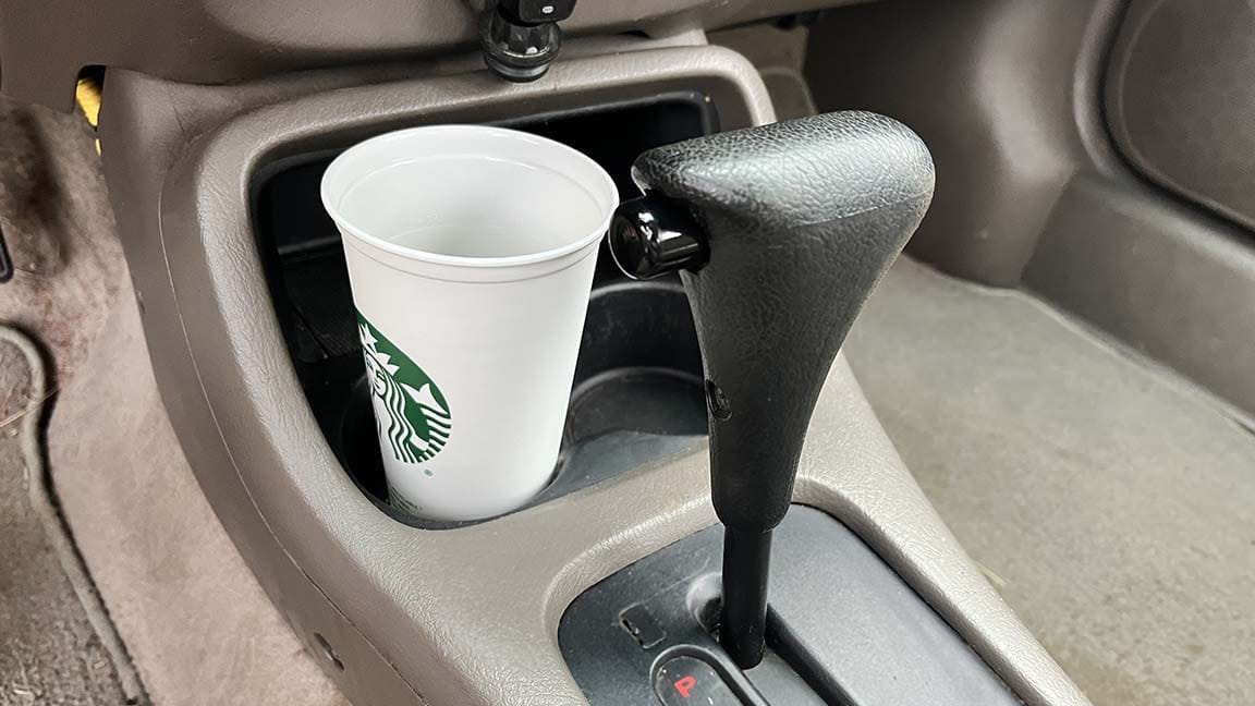 Starbucks cup in cupholder in front of gear slector