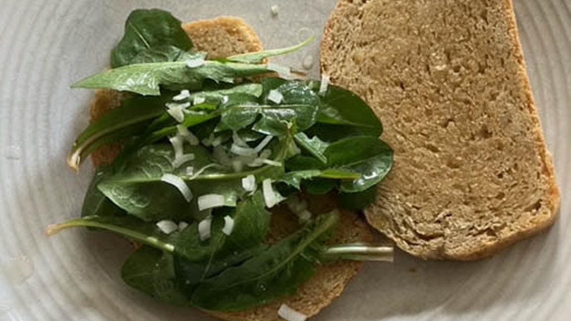 The sandwich open-faced, nice greens  on the bread, which looks like from a quality loaf