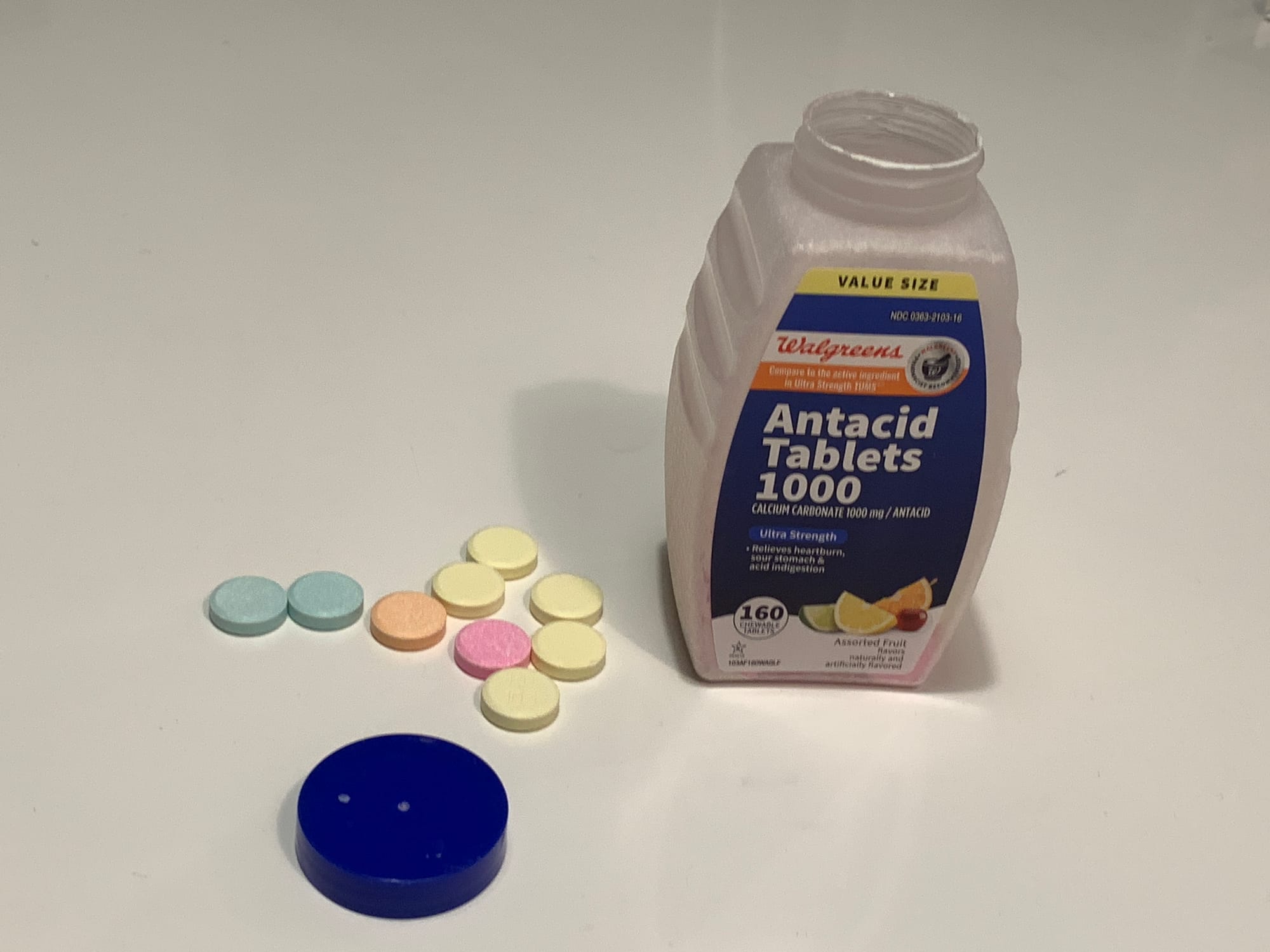 FOUR COLORS OF TABLETS NEXT TO A BOTTLE OF WALGREENS ANTACID TABLETS 1000 CALCIUM CARBONATE