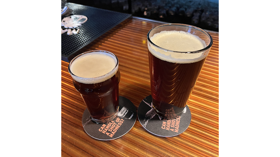 A pint of beer and a half pint of beer on coasters at the bar