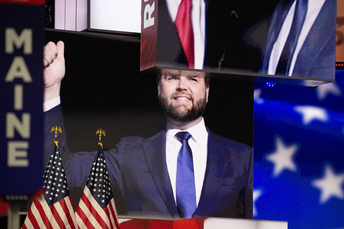 Vance sort of holding his fist up surrounded by stars & stripestrappings of the convention