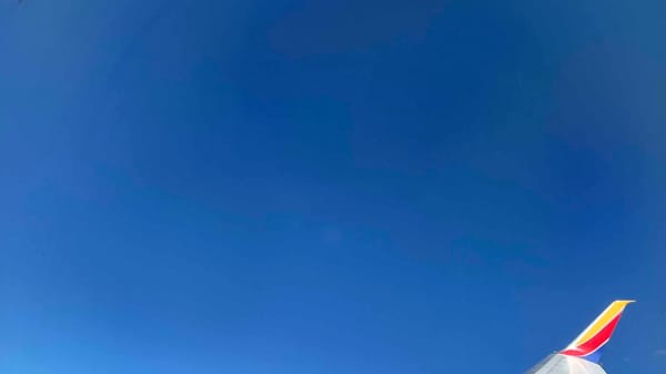 Blue sky and the wingtip of an airplane as viewed from inside plane