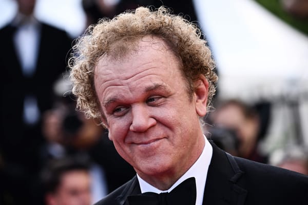 John C. Reilly in a tux with a smile/smirk on his face