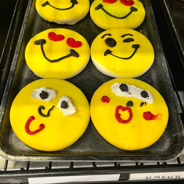 Round yellow cookies with drawn-on icing faces inspired by Internet emoji at the grocery store