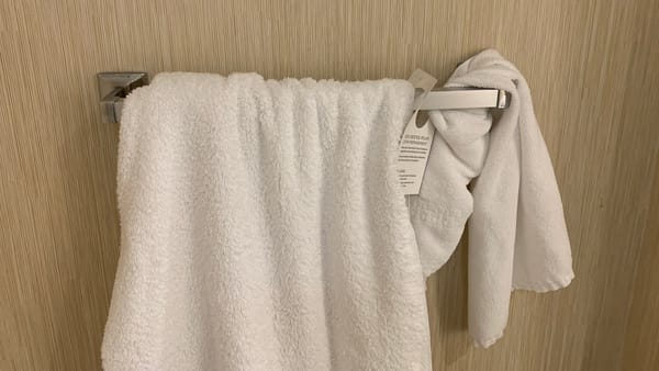 A couple-few white hotel bath towels crammed into a towel rack