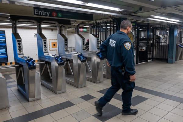 NYPD officer walking past subway turnstiles