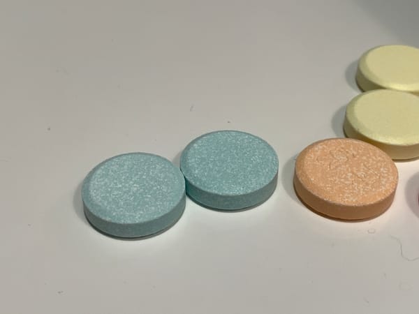 WEIRDLY GREENISH-BLUE CHALKY ANTACID TABLETS NEXT TO ORANGE AND YELLOW ONES