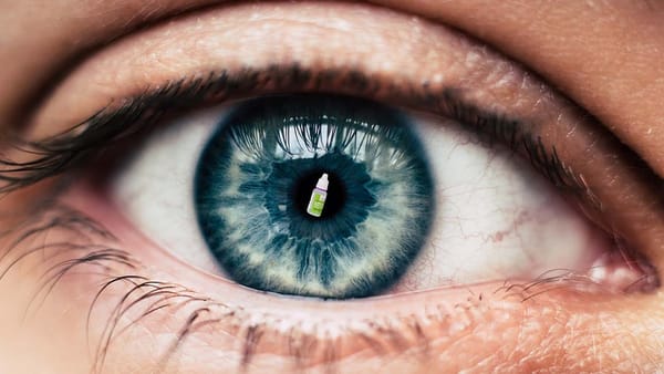 Closeup of an eye with a teeny-tiny bottle of eyedrops in the pupil