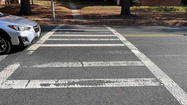 A crosswalk with a car just on the edge of entering it